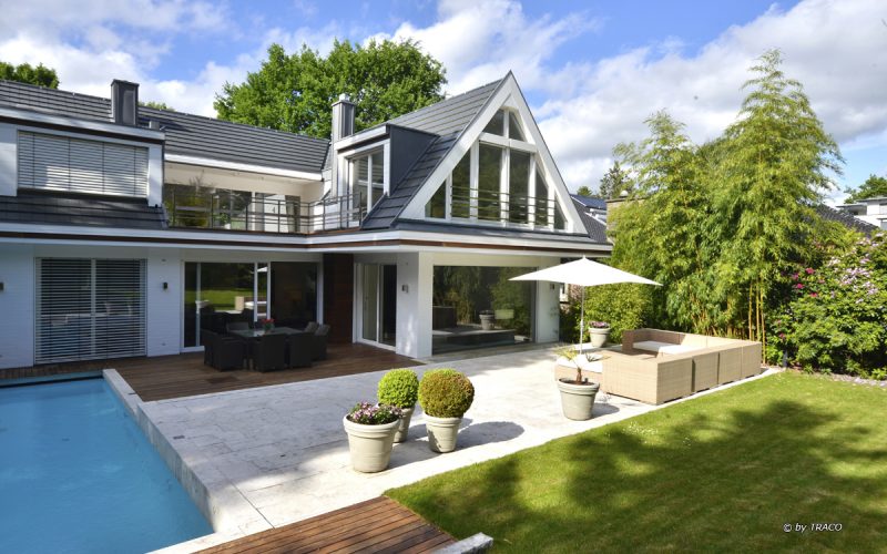 Villa mit Pooleinfassung und Terrassenplatten aus beigen Travertin Bauhaus von TRACO