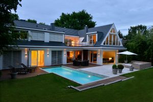 Nachtaufnahme einer Villa mit Pooleinfassung und Terrassenplatten beigen Travertin Bauhaus von TRACO