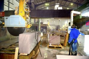 Blick in die Naturstein-Produktion von TRACO, Natursteinblock wird mit einer Säge zugeschnitten