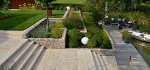 Villengarten mit Naturstein Bodenplatten, Blockstufen und Pflanzeinfassungen aus Bauhaus Travertin und Mauersteinen aus Muschelkalk